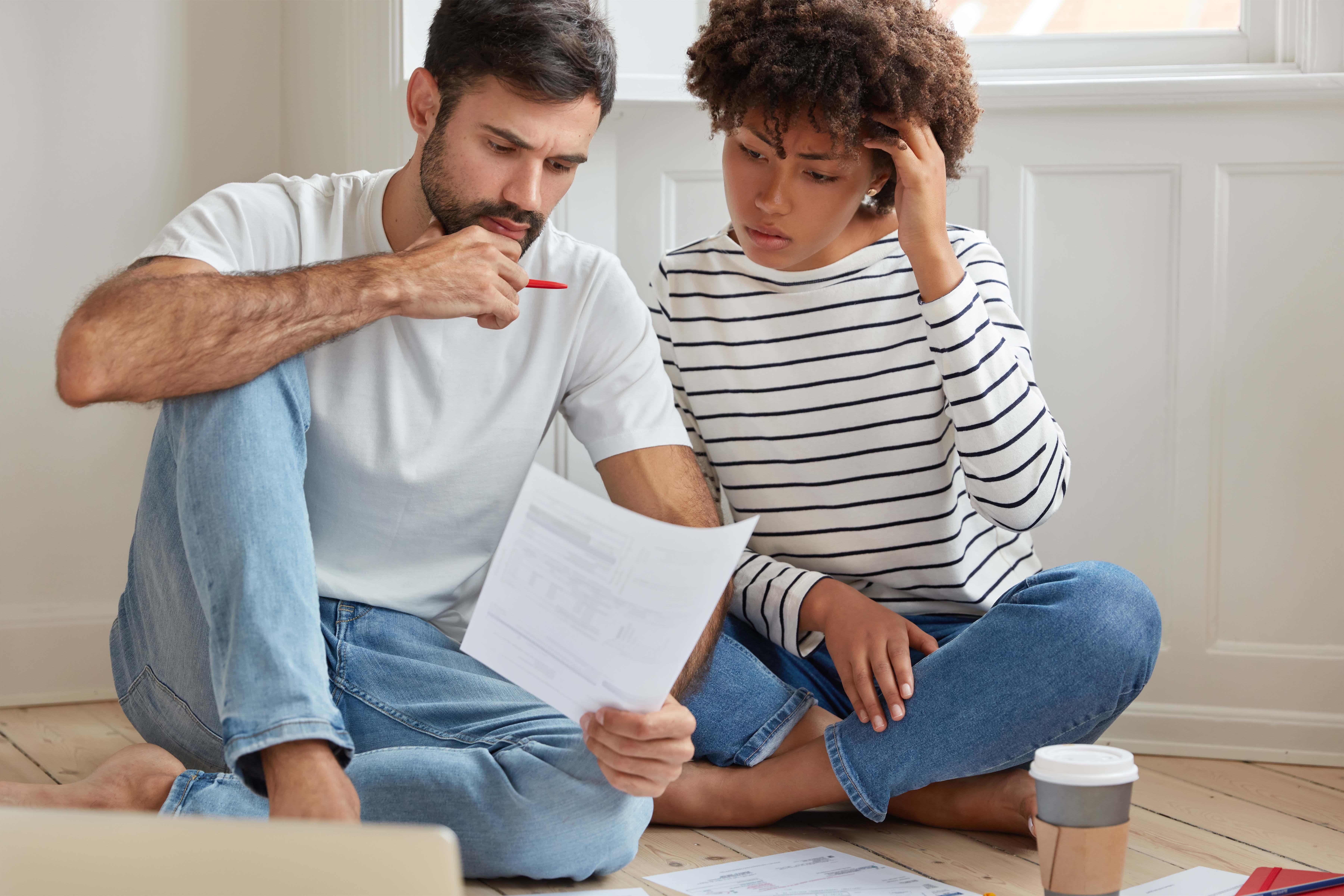  Two thoughtful young men study some papers to figure out the best strategy for buying a house on Lake Garda. 
